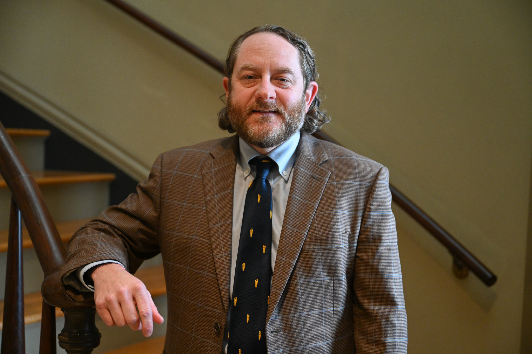 Barry standing in a suit on a staircase. 