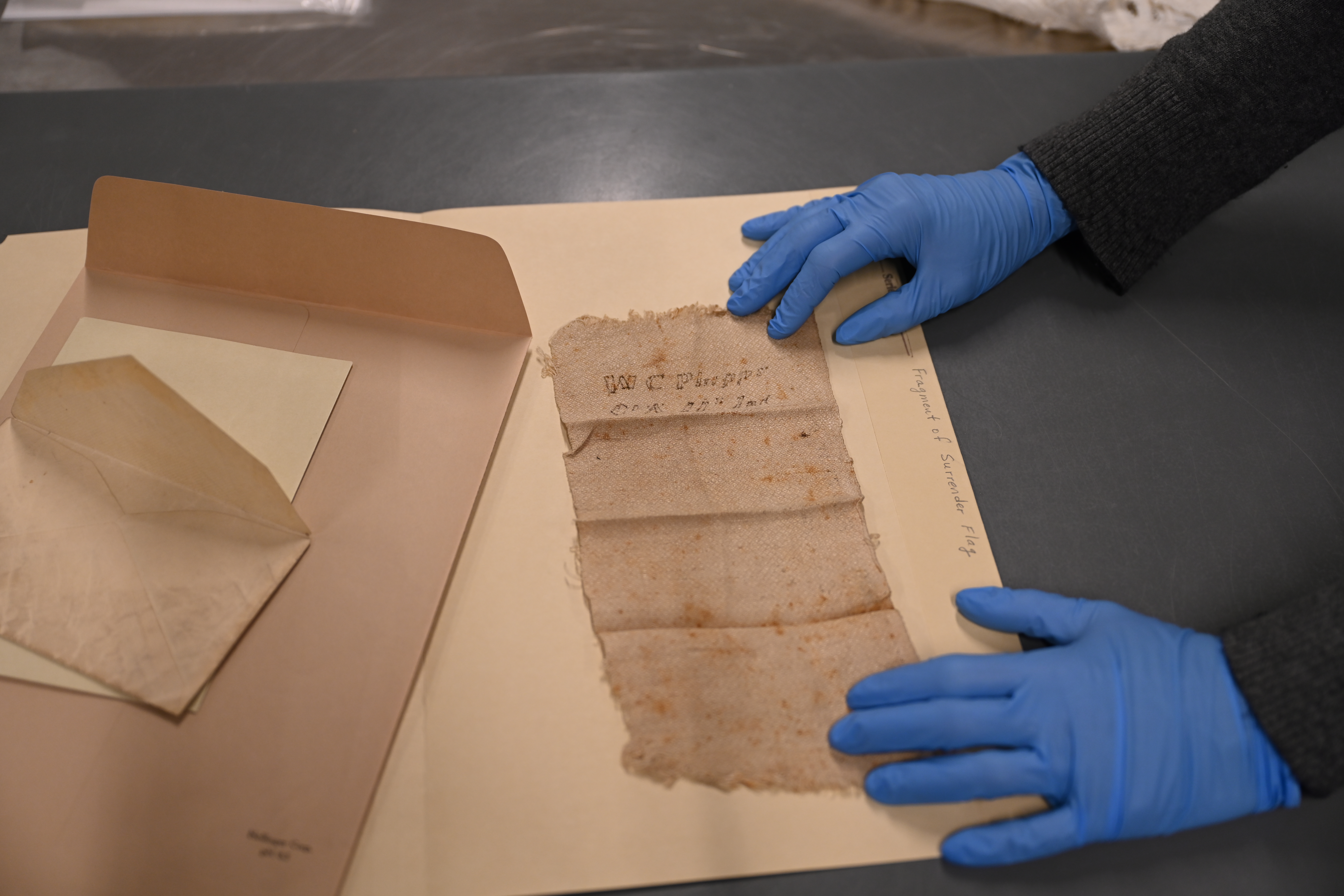 Piece of flag being examined by two gloved hands